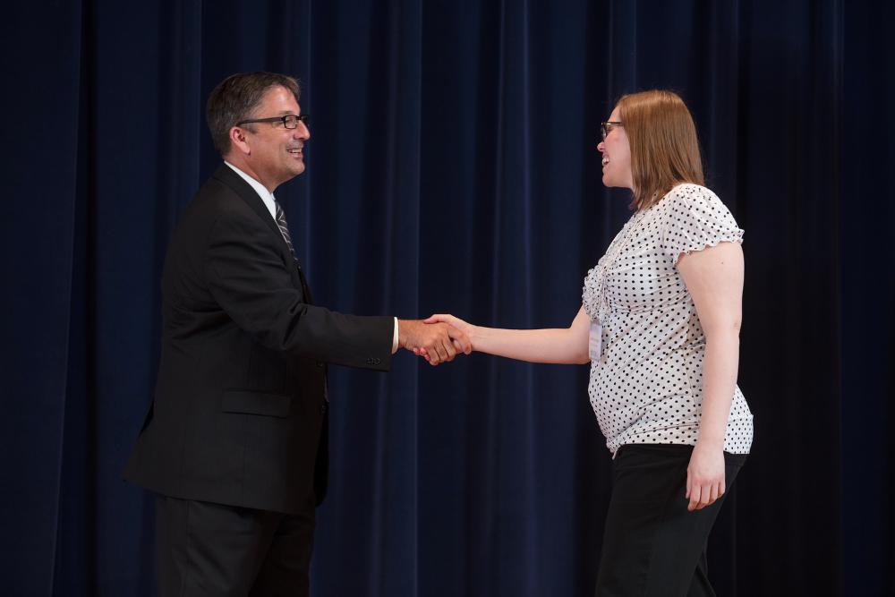 Doctor Smart shaking hands with an award recipient in a black polka dot shirt